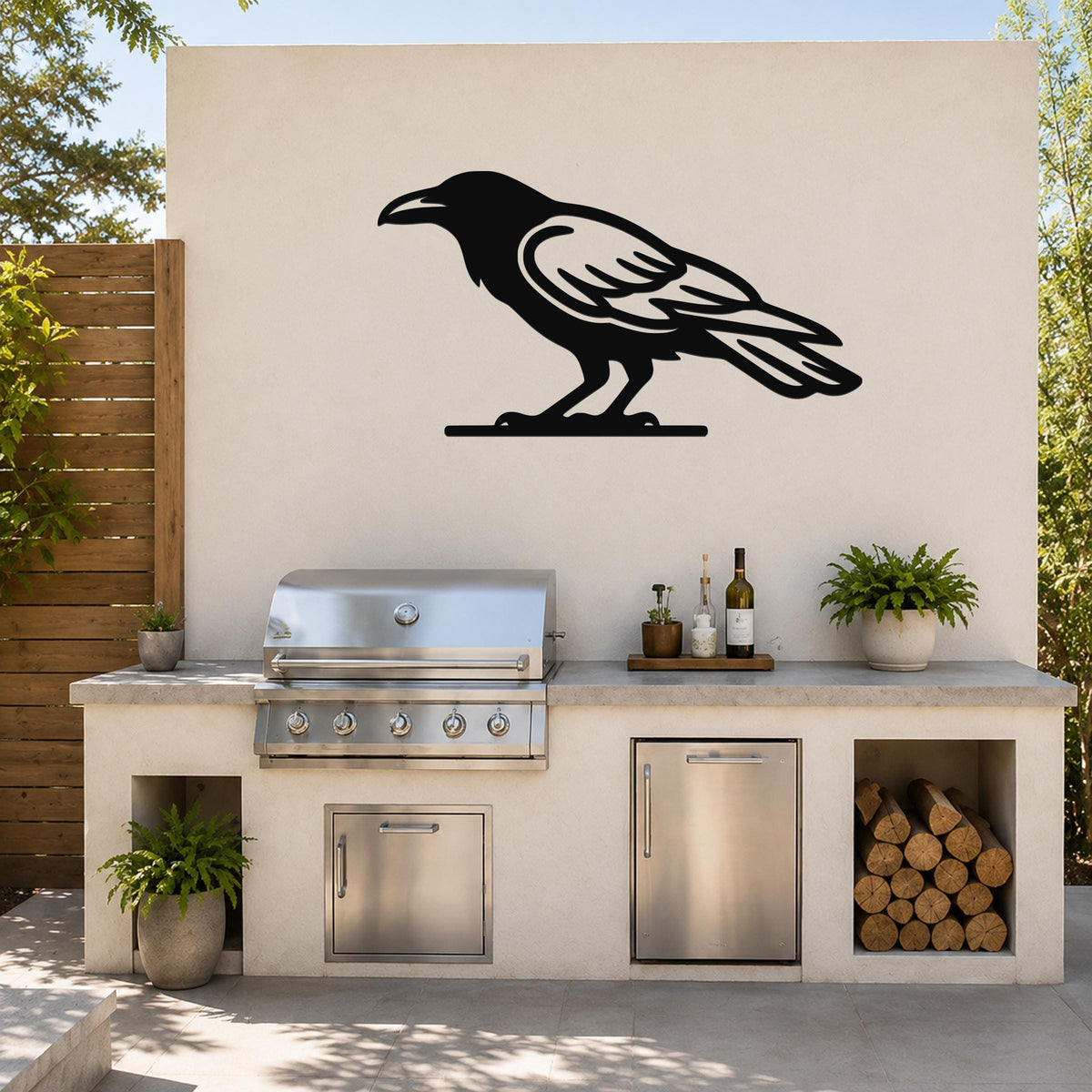 Black metal raven wall art silhouette mounted on an outdoor kitchen wall above a stainless steel grill and counter.