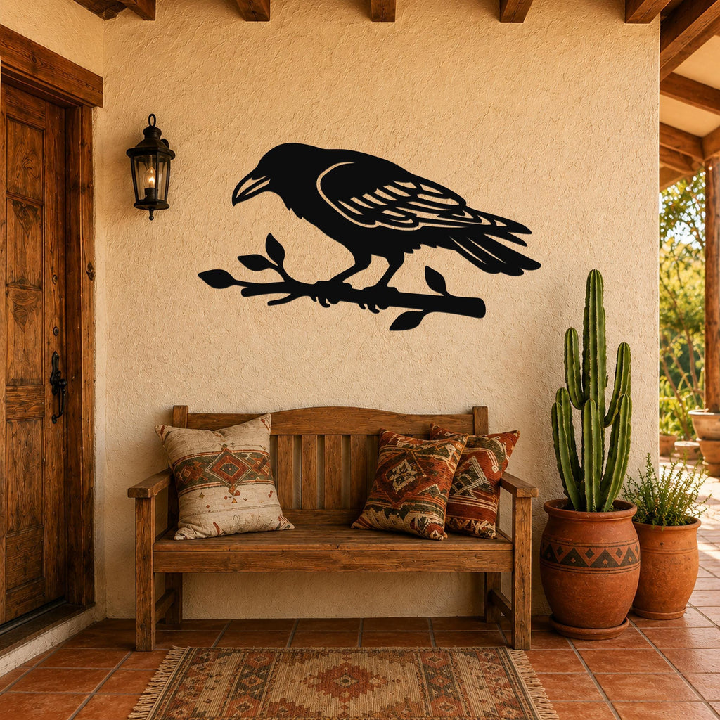 Black metal raven wall art with detailed feather cutouts, perched on a branch, mounted on a stucco wall above a wooden bench in a rustic patio entryway.