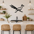 Black metal roadrunner wall art with motion-line cutouts, mounted above a kitchen counter in a modern kitchen.