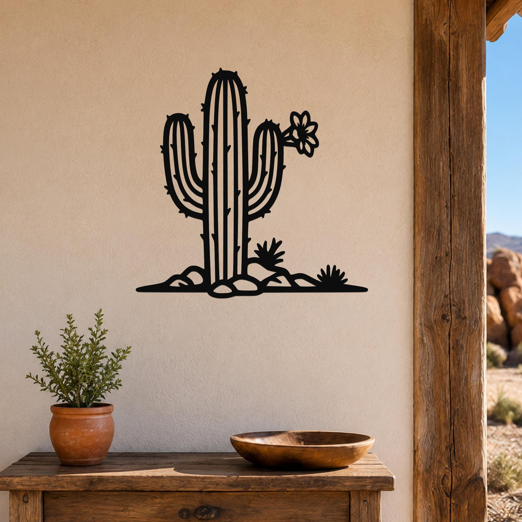 Black metal saguaro cactus wall art with flower and small plants cutouts, mounted on a beige wall above a wooden table in a southwestern-style room.