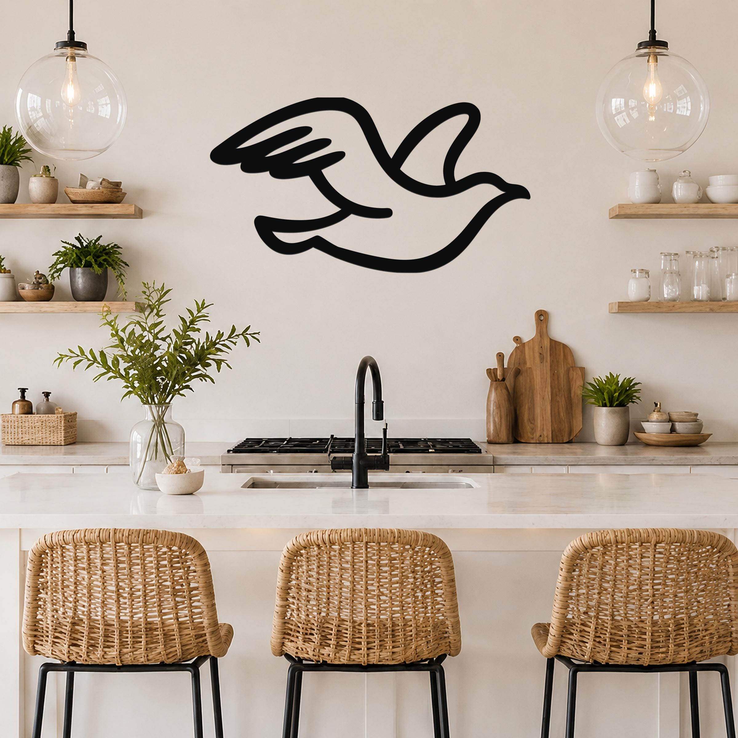 Black metal seagull wall art with motion-line cutouts, mounted above a kitchen counter in a bright, modern kitchen.