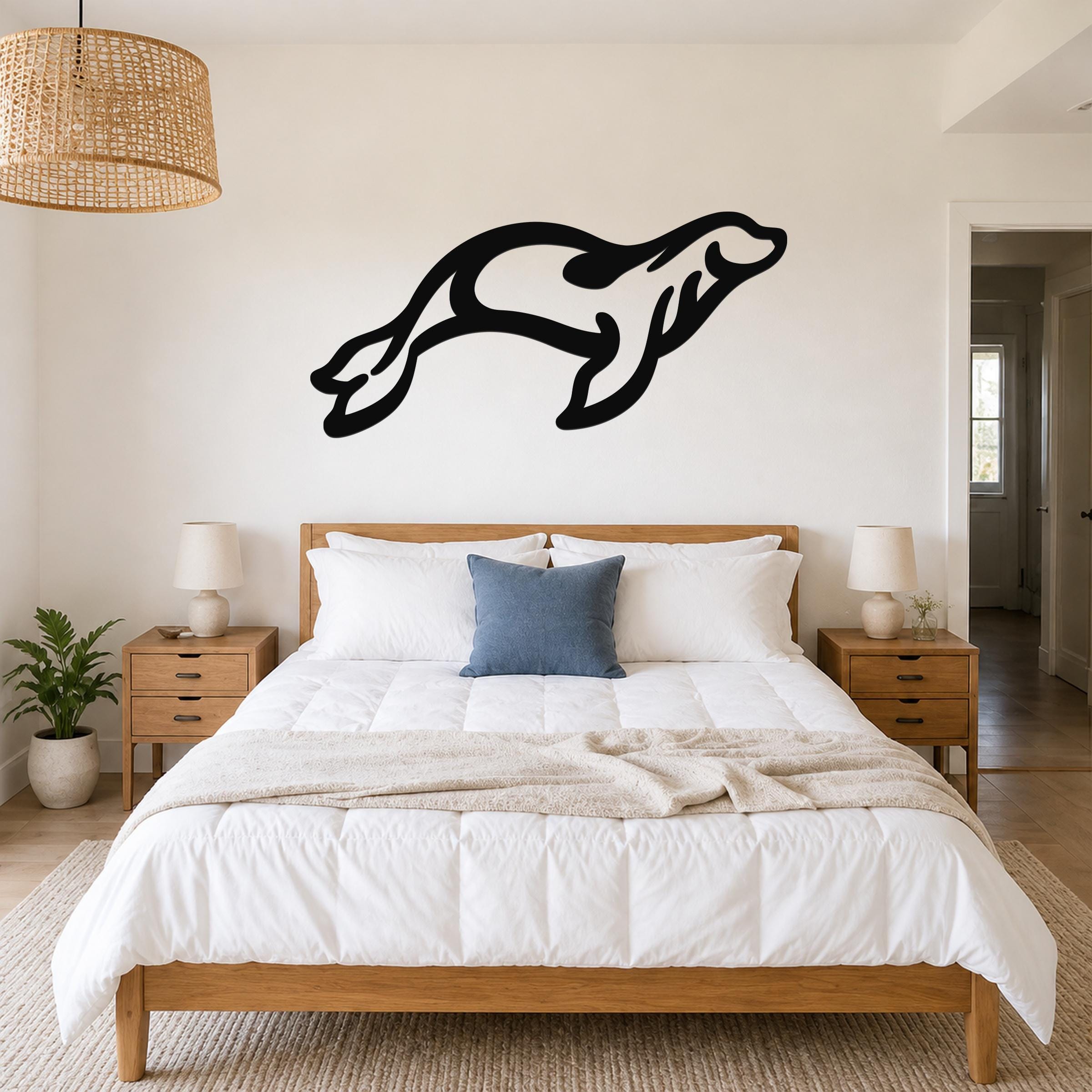 Black metal sea lion wall art in a dynamic leaping silhouette, mounted above a wooden bed in a bright bedroom.