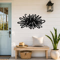Black metal sea urchin wall art with spiky, radiating cutouts, mounted on a white shiplap wall above a wooden bench in a coastal entryway.