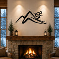 Black metal skier and mountain wall art with motion-line cutouts, mounted above a stone fireplace in a cozy living room.