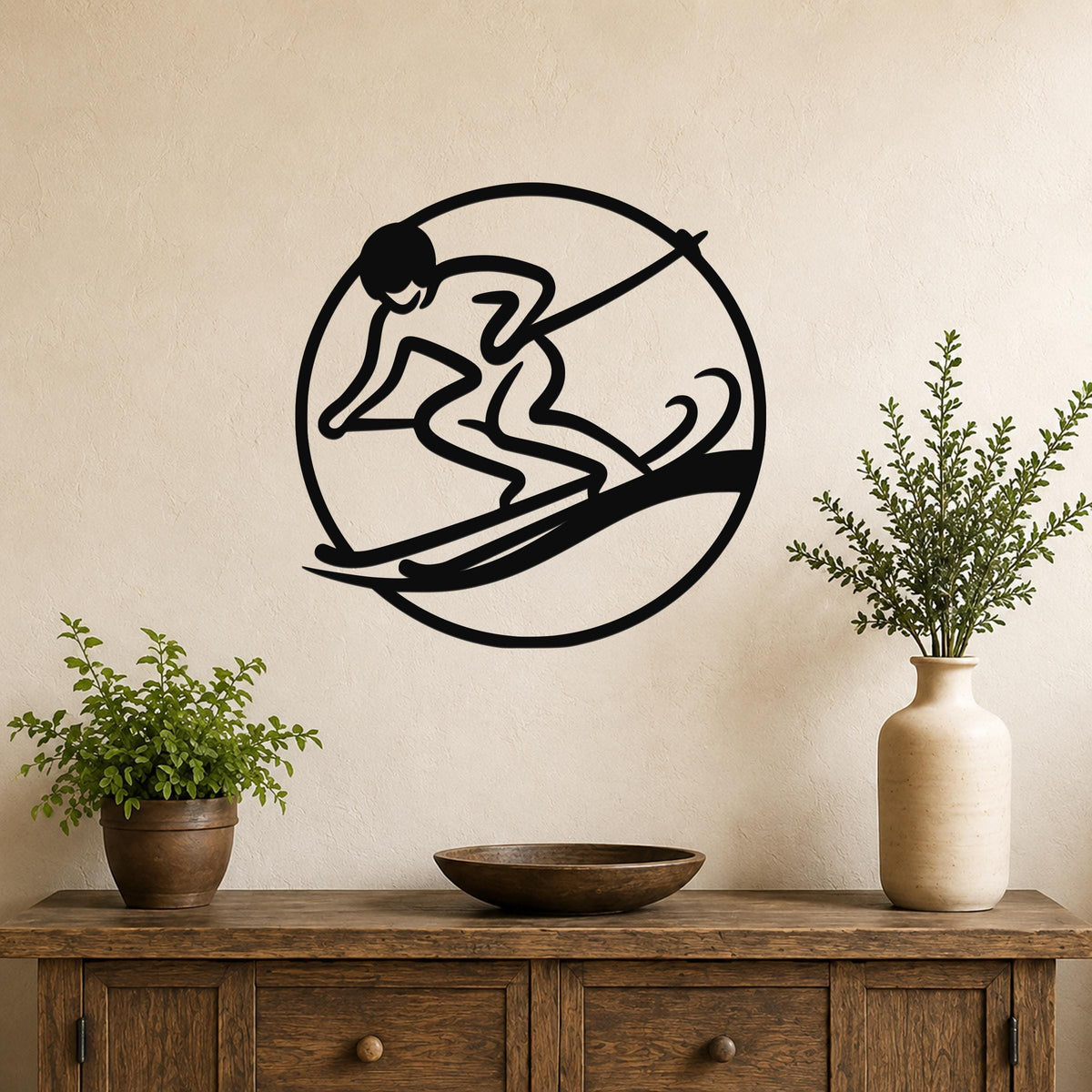 Black metal wall art featuring a circular silhouette of a skier in motion, mounted on a beige wall above a wooden console table with potted plants.