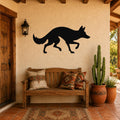Black metal coyote wall art silhouette mounted on a stucco wall above a wooden bench in a patio entryway.