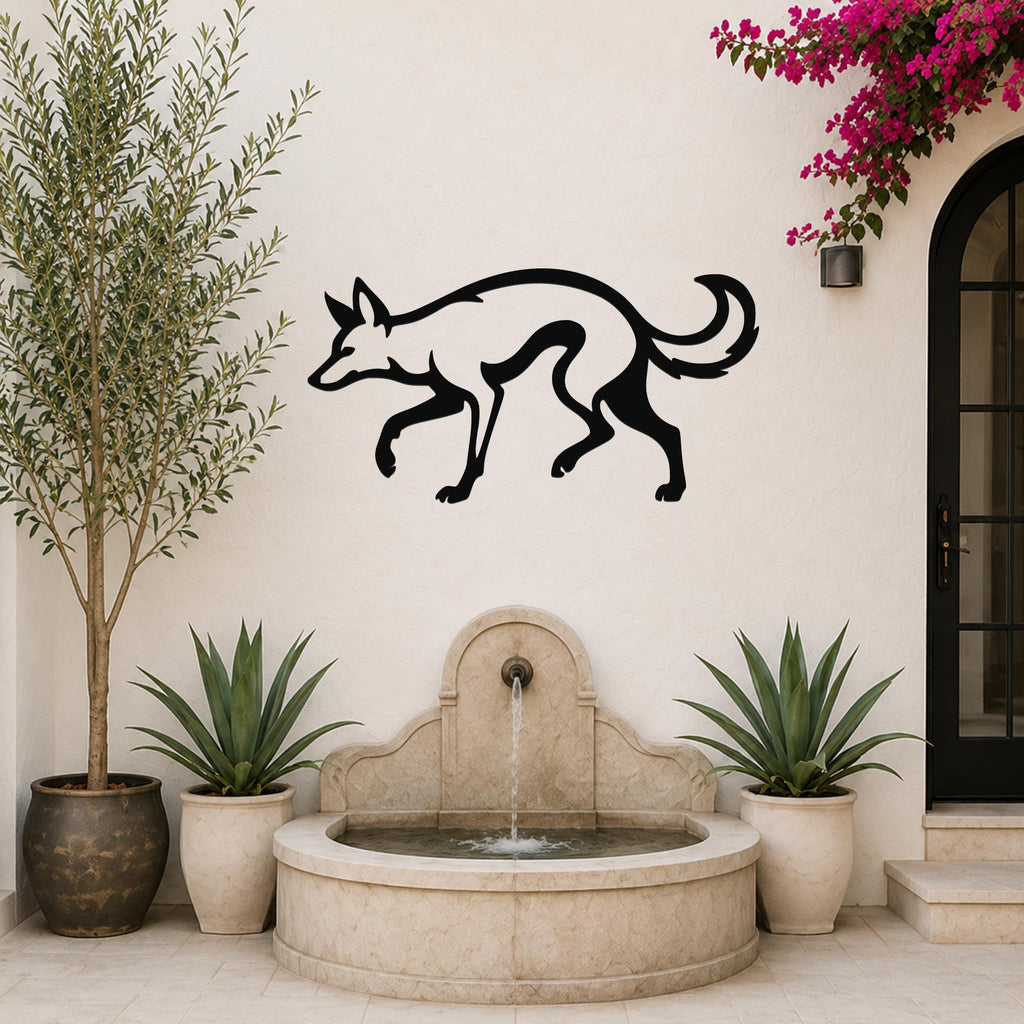 Black metal coyote wall art silhouette mounted on a white outdoor wall above a stone fountain, flanked by potted plants and a blooming vine.