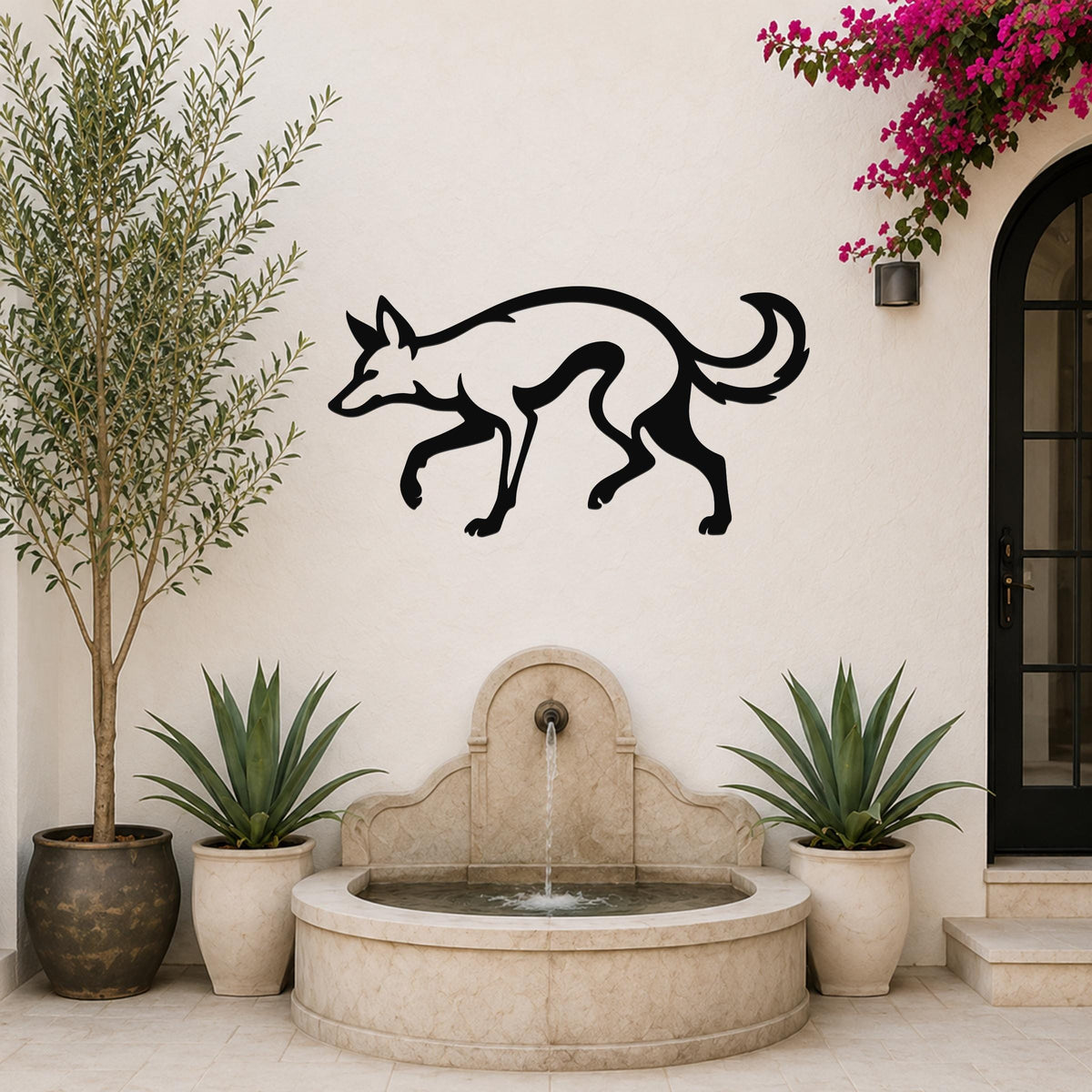 Black metal coyote wall art silhouette mounted on a white outdoor wall above a stone fountain, flanked by potted plants and a blooming vine.