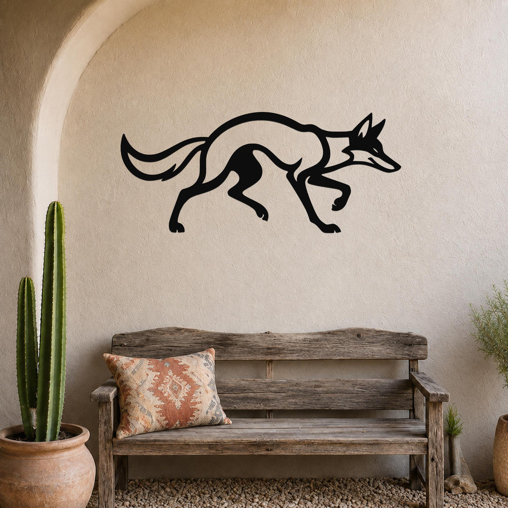 Black metal coyote wall art in a running silhouette, mounted on a textured beige wall above a rustic wooden bench in a patio setting.