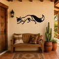 Black metal fox wall art silhouette with motion-line cutouts, mounted above a wooden bench on a stucco wall in a rustic patio entryway.
