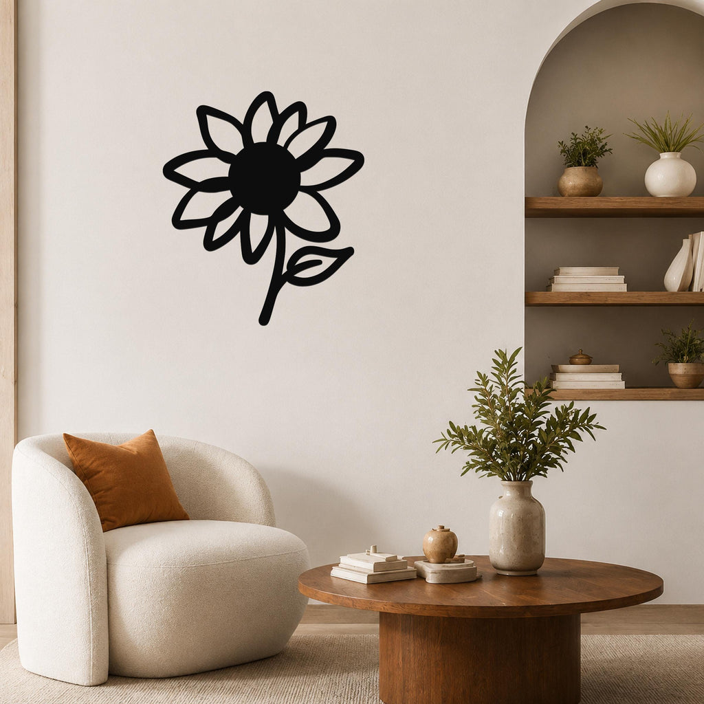 Black metal sunflower wall art with a bold silhouette design, mounted on a living room wall above a white armchair.