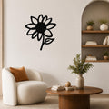 Black metal sunflower wall art with a bold silhouette design, mounted on a living room wall above a white armchair.