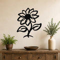 Black metal sunflower wall art with a cutout silhouette design, mounted on a beige wall above a wooden console table with potted plants.