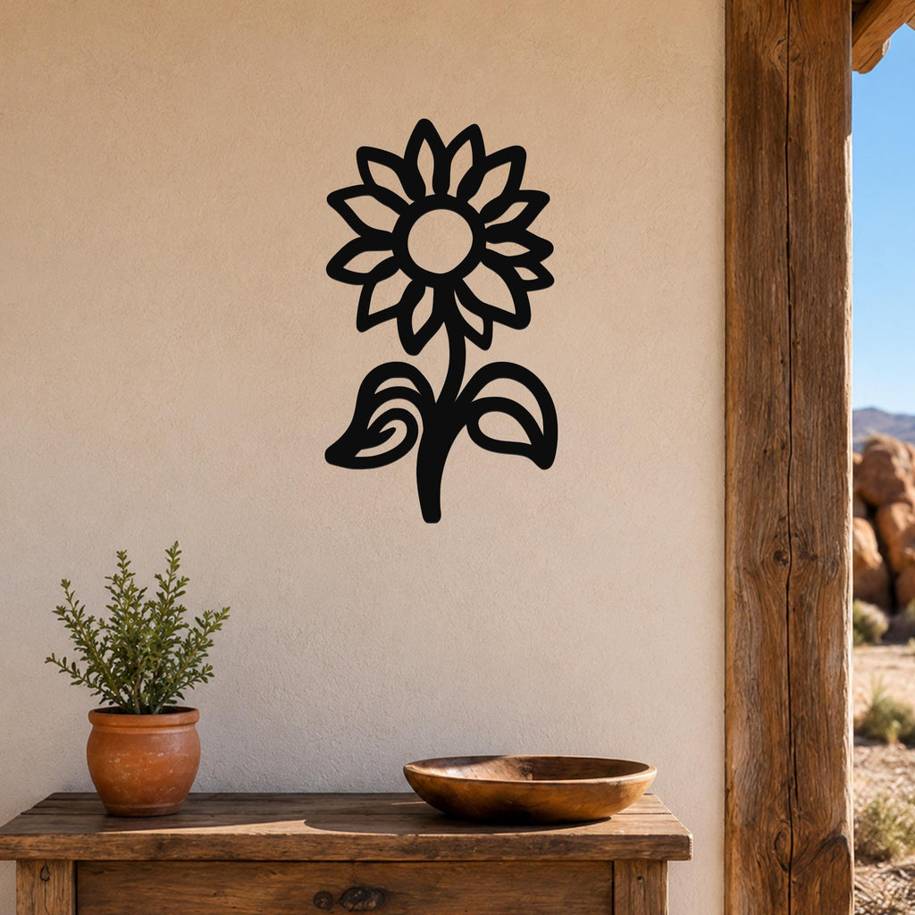 Black metal sunflower wall art with a silhouette design, mounted on a beige wall above a wooden table with a potted plant and bowl.
