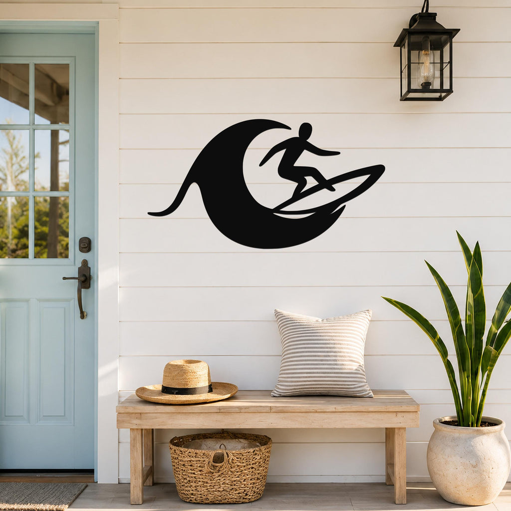 Black metal wall art featuring a surfer silhouette riding a wave, mounted on a white shiplap wall above a wooden bench in a coastal entryway.