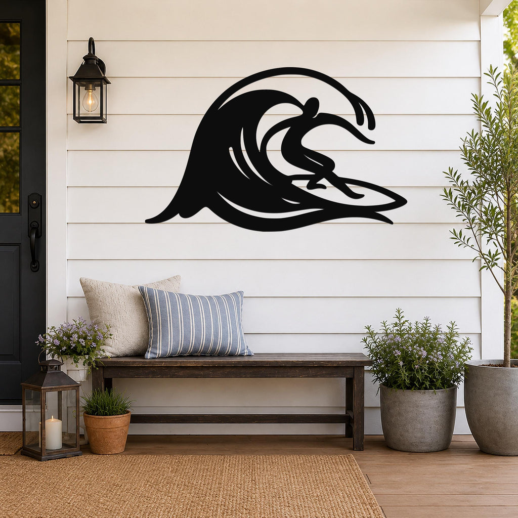 Black metal wall art cutout of a surfer riding a flowing wave, mounted on a white shiplap wall above a wooden bench on a porch.