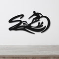 Black metal wall art featuring a surfer silhouette riding a wave, mounted on a white wall above a light wood counter.