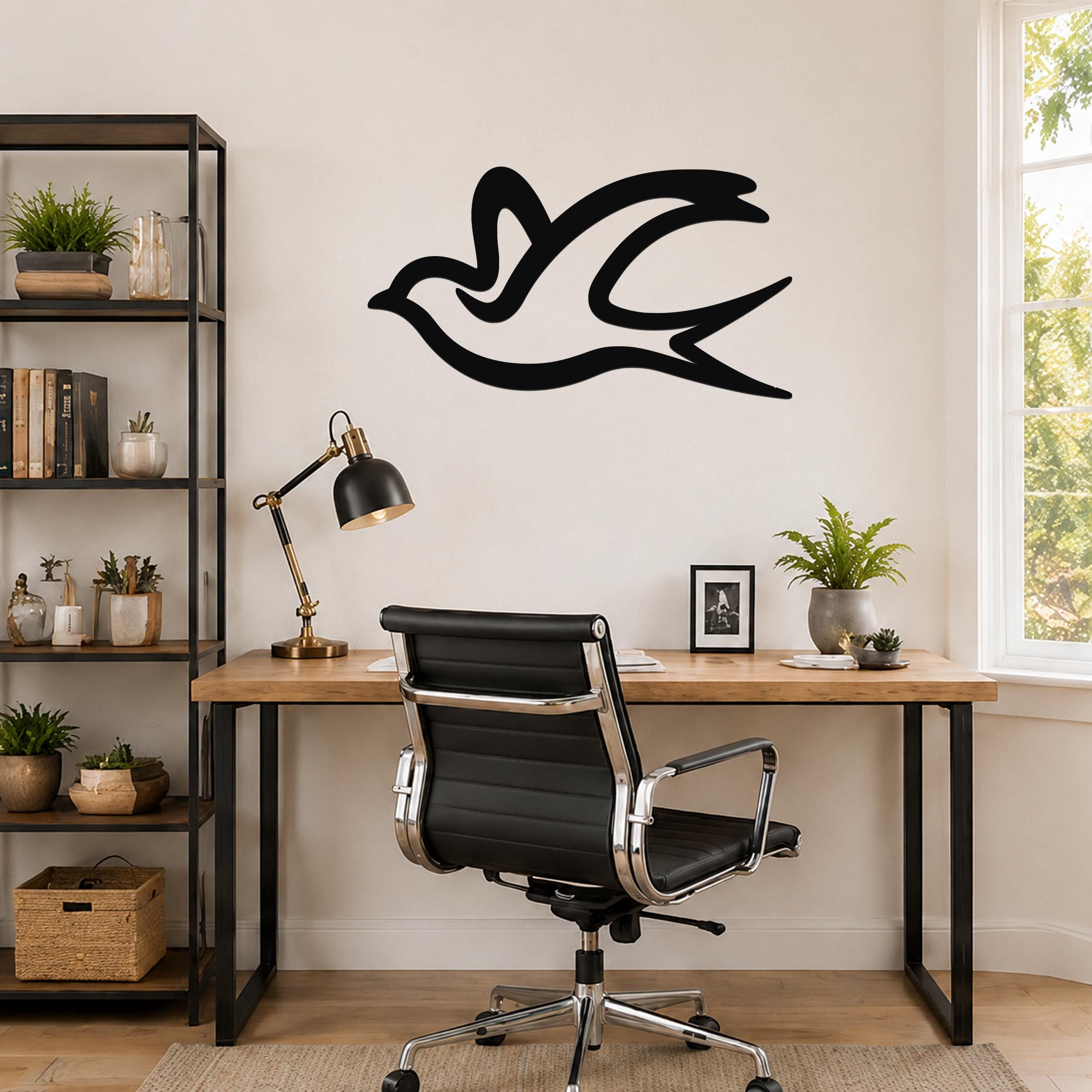 Black metal swallow bird wall art with motion-line cutouts, mounted above a wooden desk in a home office.