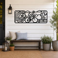 Black metal triathlon wall art with swim, bike, and run silhouettes and motion lines, mounted on a white shiplap wall above a wooden bench on a porch.