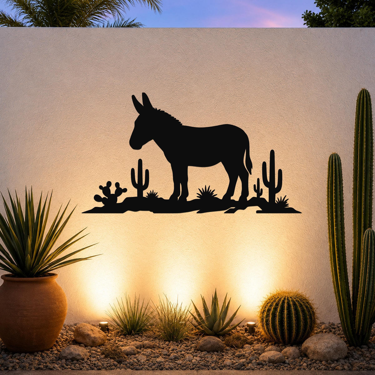 Black metal wall sculpture of a burro silhouette with cacti, mounted on an outdoor wall above a desert garden with potted plants and ground lights.