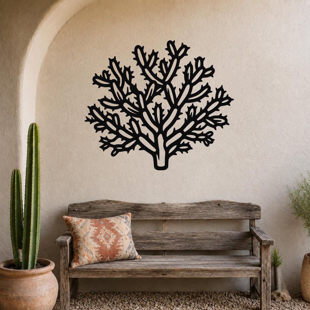 Black metal Cholla cactus wall art with intricate branch cutouts, mounted on a textured beige wall above a rustic wooden bench in a desert-themed entryway.