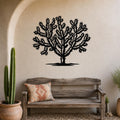 Black metal wall art of a cholla cactus silhouette with intricate branching cutouts, mounted on a textured beige wall above a rustic wooden bench in a southwestern-style entryway.