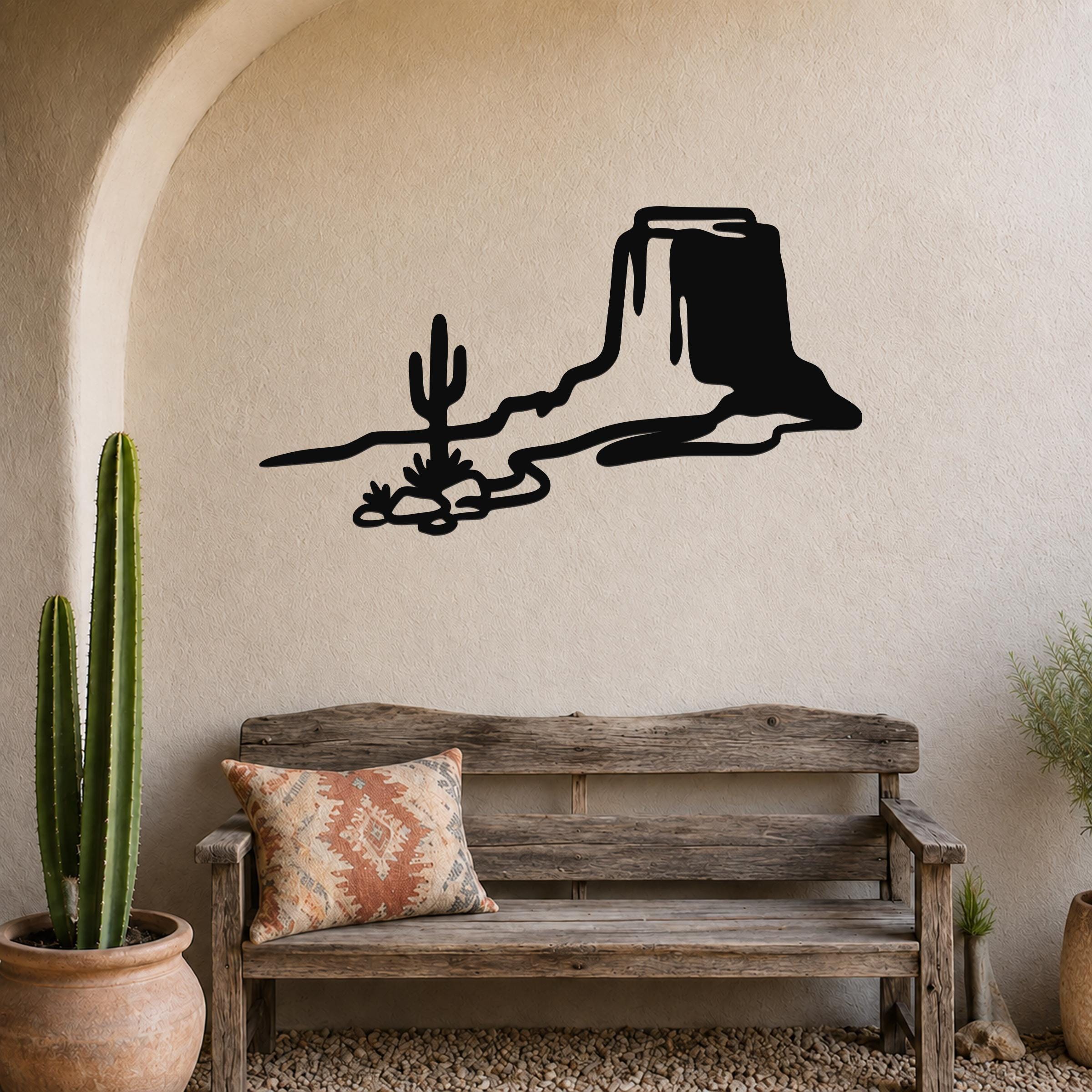 Black metal wall art silhouette of a desert mesa and cactus, mounted above a wooden bench in a southwestern-style entryway.