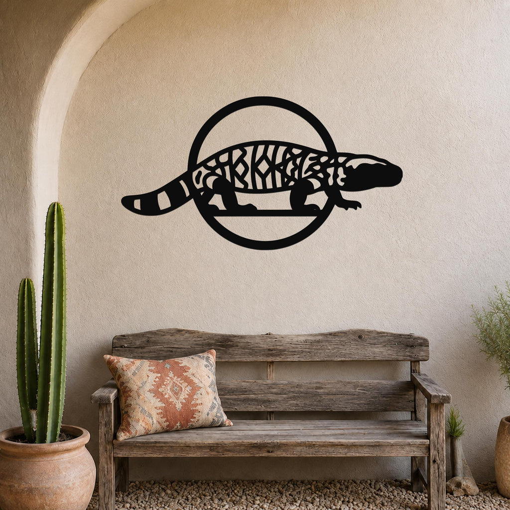 Black metal Gila monster wall art with intricate internal cutouts, mounted on a textured beige wall above a rustic wooden bench in a southwestern-style entryway.