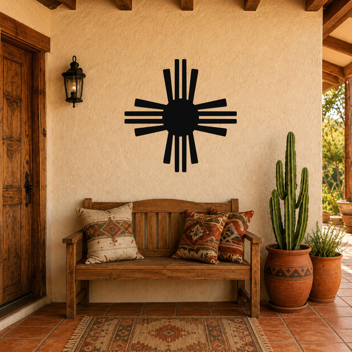 Black metal Zia Sun symbol wall art with eight rays, mounted on a stucco wall above a wooden bench in a southwestern-style entryway.