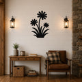 Black metal wall art featuring a silhouette of three daisies with long stems and leaves, mounted on a shiplap wall above a wooden console table in a living room.