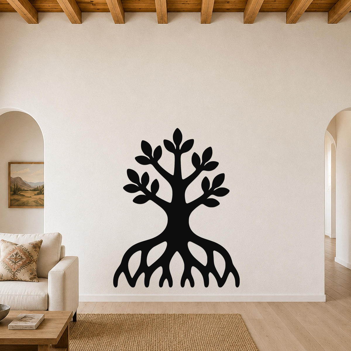 Black metal wall art in the shape of a tree with visible roots and leafy branches, mounted on a living room wall above a sofa.