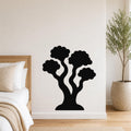 Black metal wall art in a stylized tree silhouette with multiple rounded canopies, mounted on a white bedroom wall above a bed.