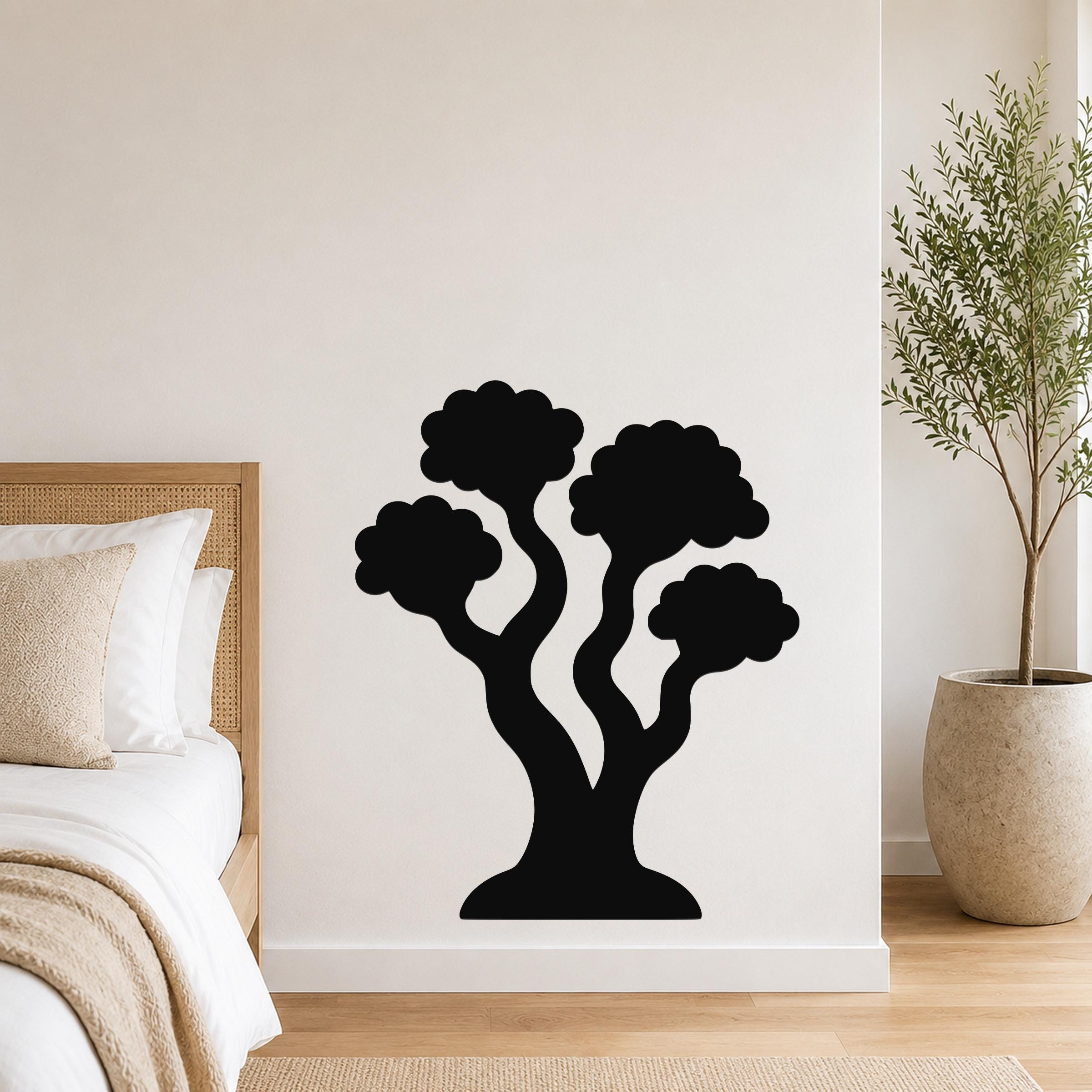Black metal wall art in a stylized tree silhouette with multiple rounded canopies, mounted on a white bedroom wall above a bed.