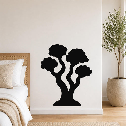 Black metal wall art in a stylized tree silhouette with multiple rounded canopies, mounted on a white bedroom wall above a bed.