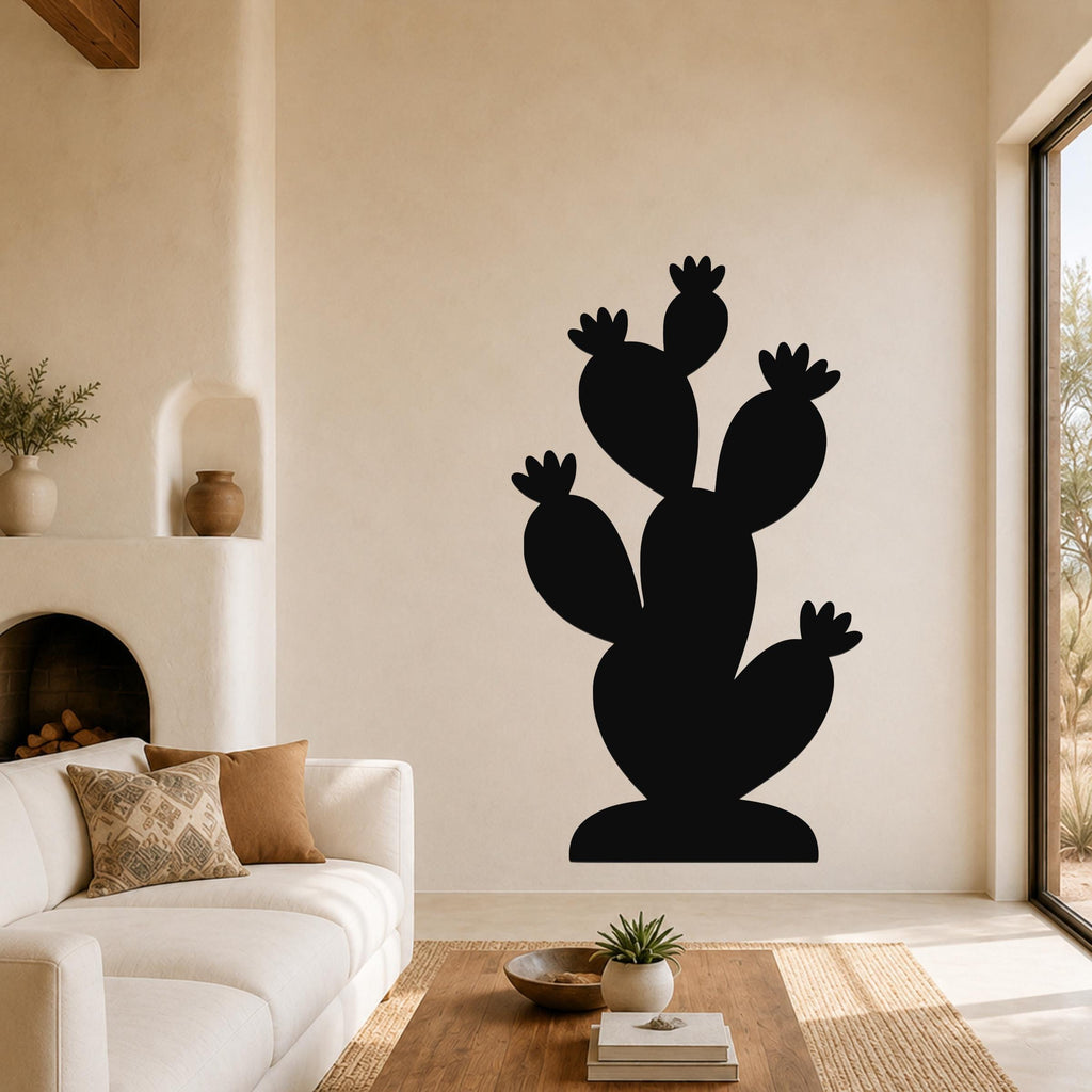 Black metal prickly pear cactus wall art with multiple pads and flower cutouts, mounted on a living room wall above a white sofa.