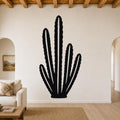 Black metal wall art cutout of an organ pipe cactus with multiple vertical arms, mounted on a living room wall above a sofa.