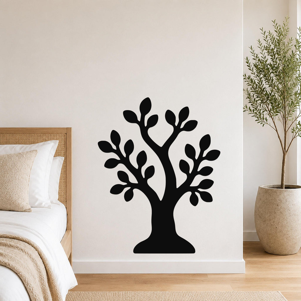 Black metal wall art in the shape of a tree with leafy branches, mounted on a white wall above a bed in a bedroom.