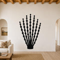 Black metal ocotillo wall art with branching stem and bead-like cutouts, mounted on a living room wall above a sofa.