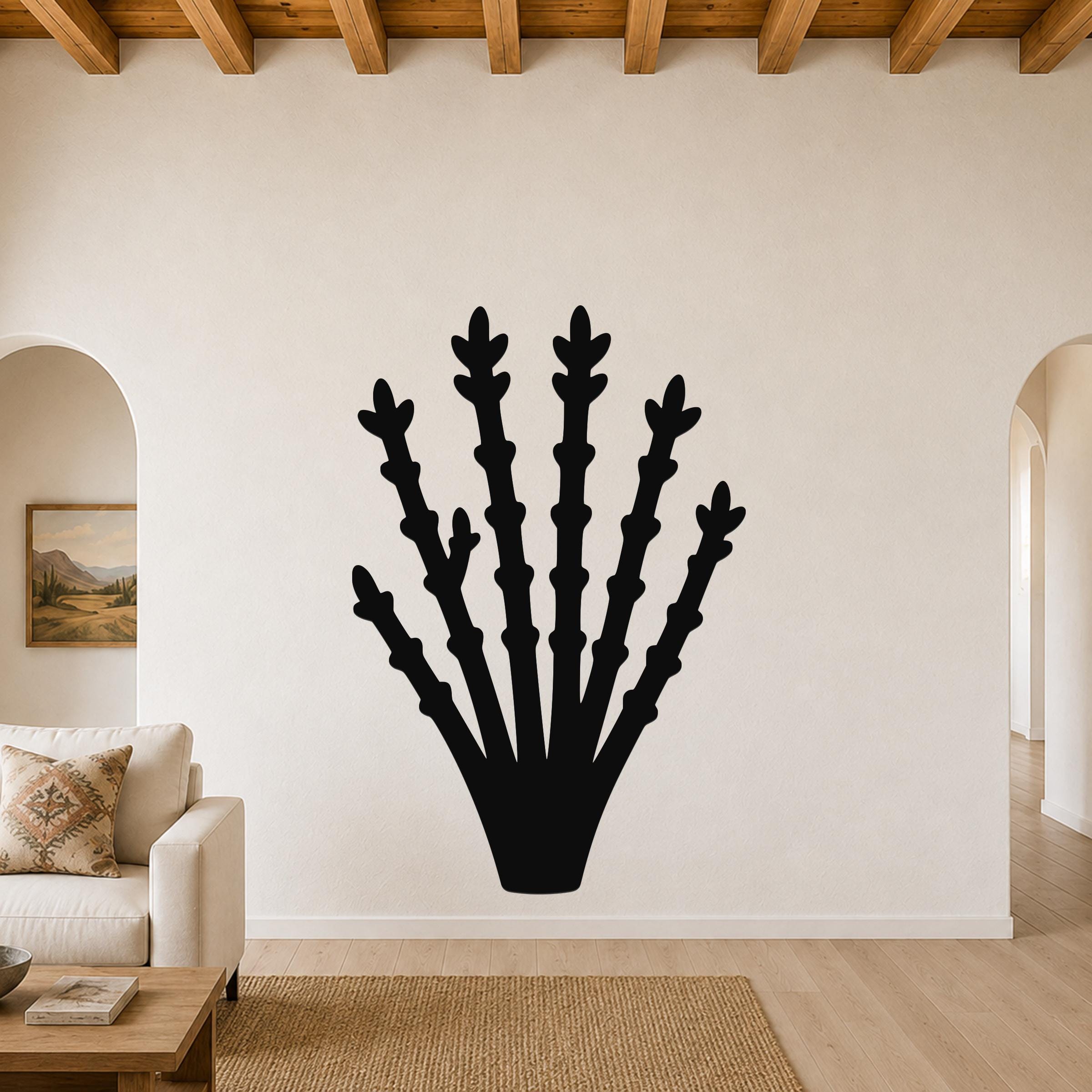 Black metal ocotillo wall art with branching stem cutouts, mounted on a living room wall above a sofa.