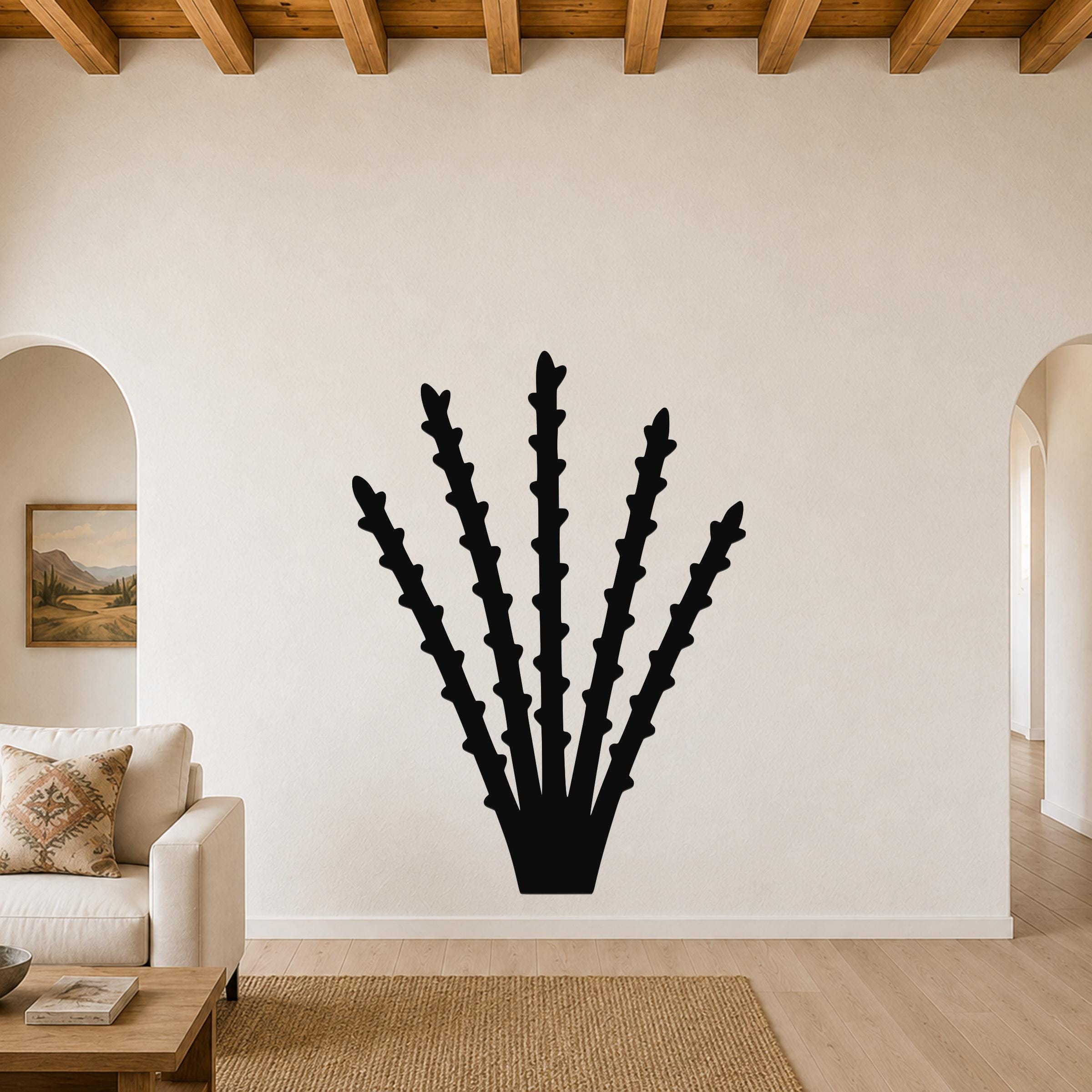 Black metal ocotillo wall art with spiky branch cutouts, mounted on a living room wall above a sofa.