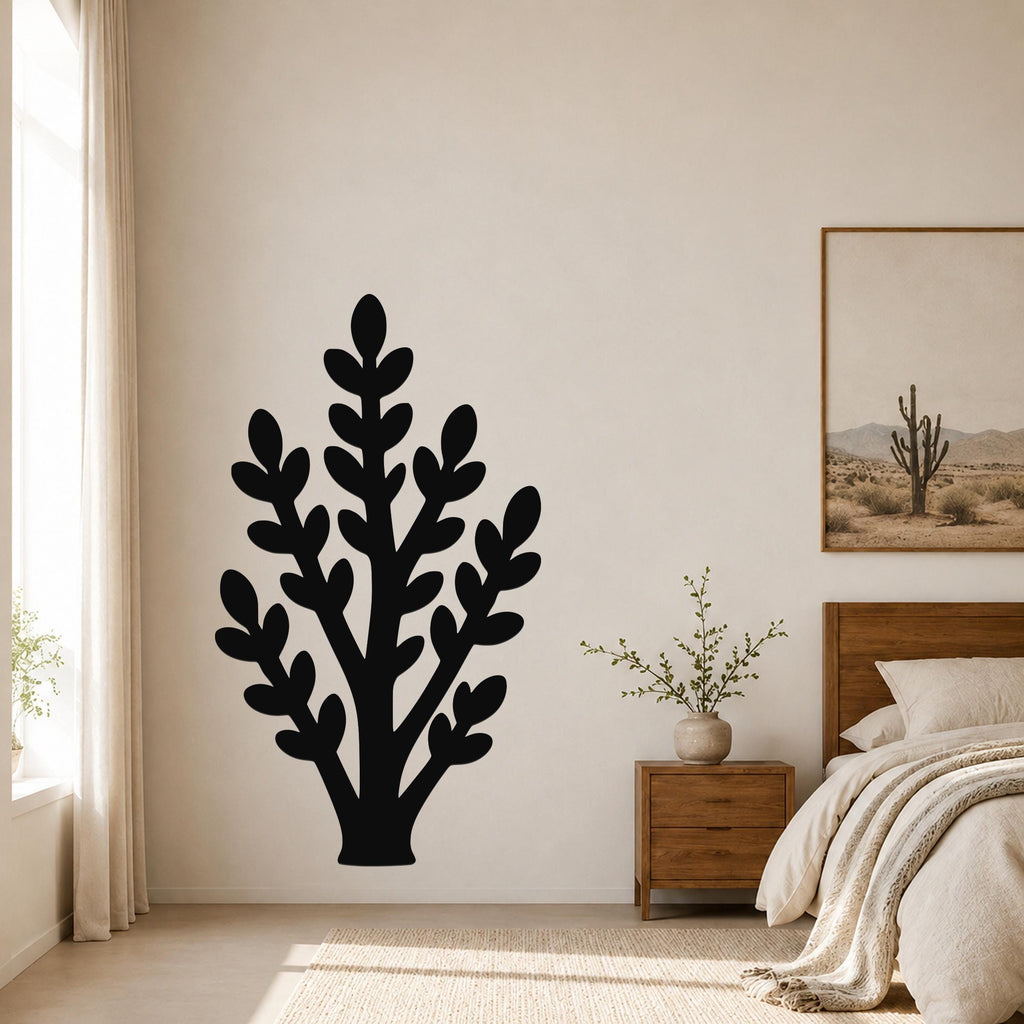 Black metal wall art in the shape of a jade plant silhouette, mounted on a bedroom wall above a wooden nightstand.