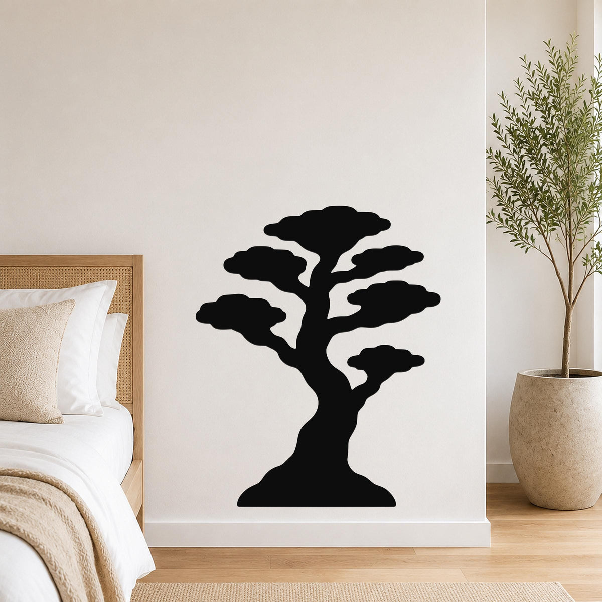 Black metal bonsai tree wall art with layered canopy cutouts, mounted on a white bedroom wall above a bed.