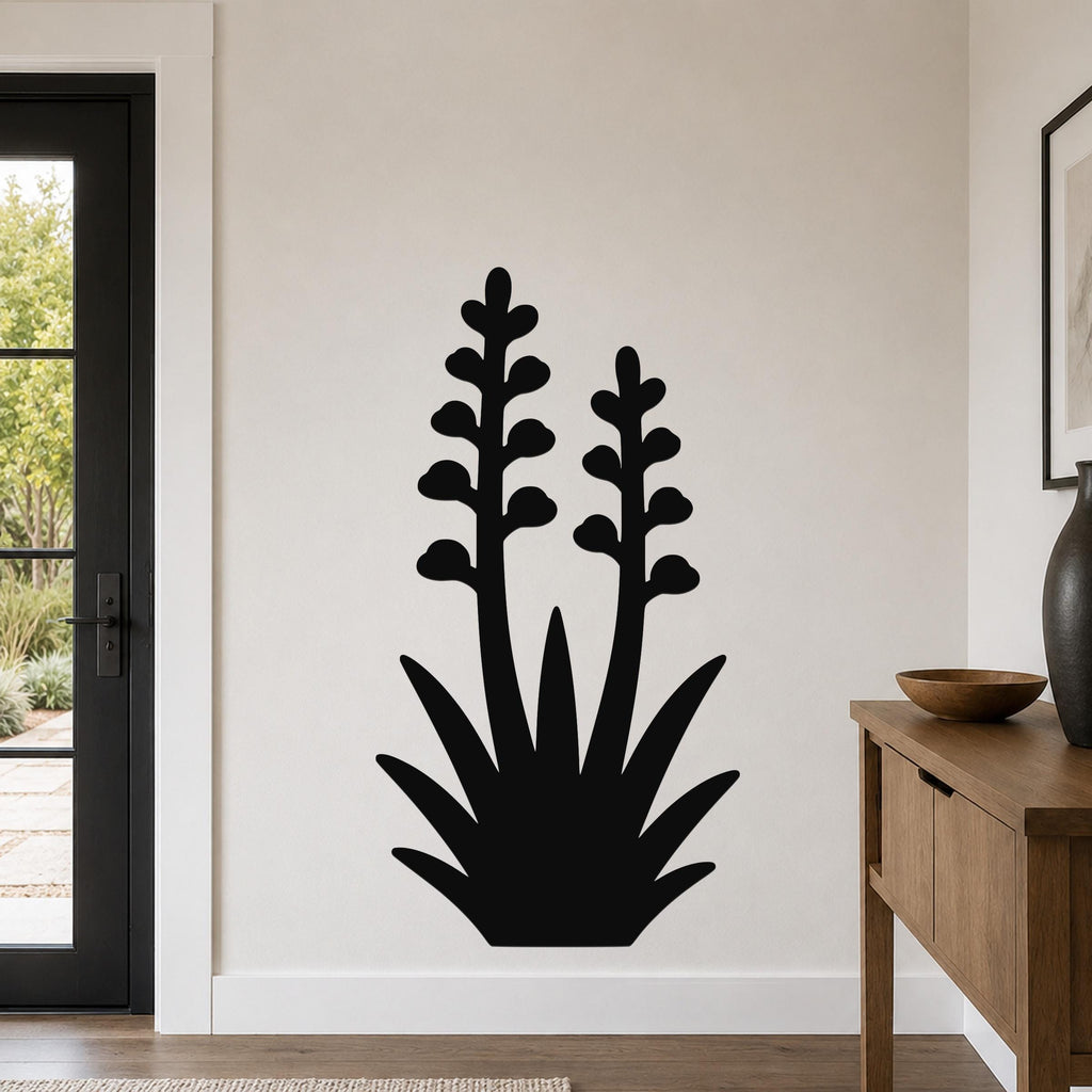 Black metal wall art in the silhouette of a blooming agave plant with two tall flower stalks and spiky base, mounted on a light-colored wall in a modern entryway.