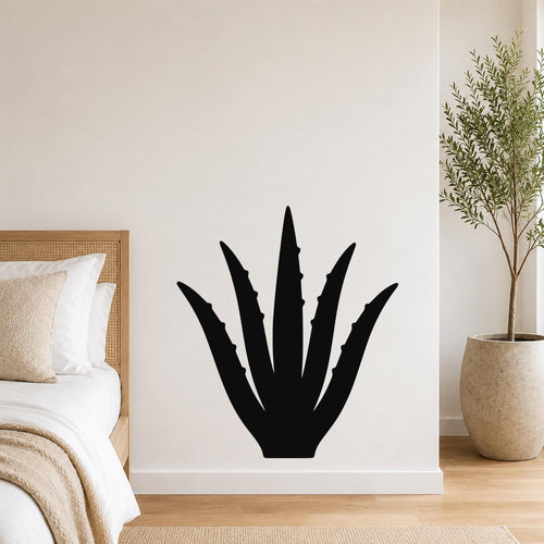 Black metal agave wall art with spiky leaf cutouts, mounted on a white bedroom wall above a bed.