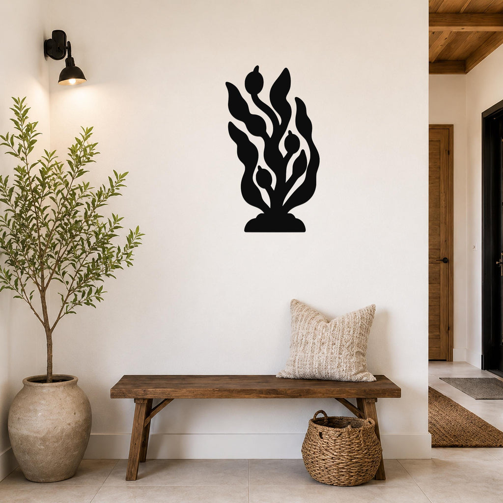 Black metal kelp and seaweed wall art with leafy cutouts, mounted on a white wall above a wooden bench in a modern entryway.