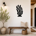 Black metal kelp and seaweed wall art with leafy cutouts, mounted on a white wall above a wooden bench in a modern entryway.