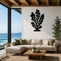 Black metal kelp wall art with leafy cutouts, mounted on a white living room wall above a beige sectional sofa.