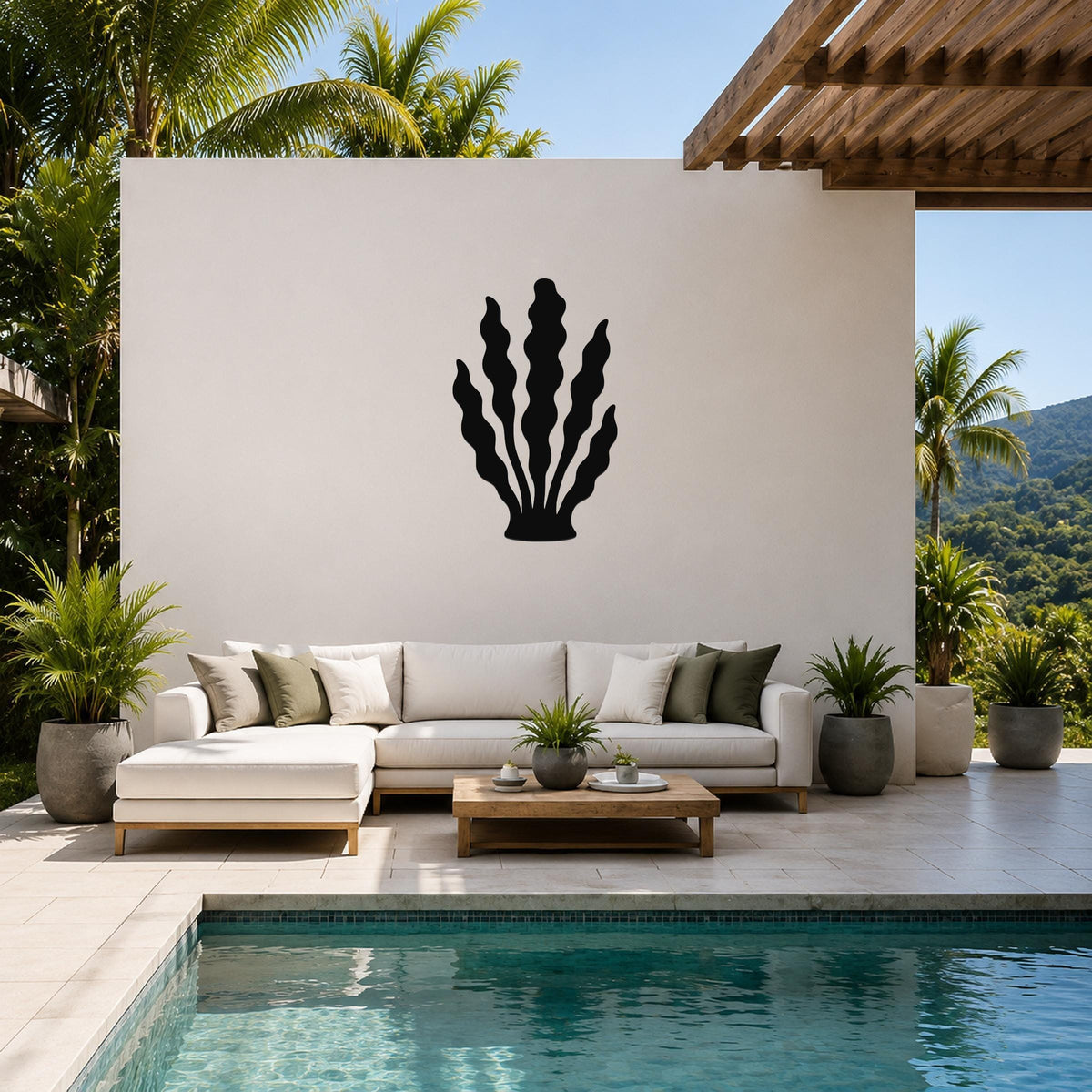 Black metal kelp wall art with wavy frond cutouts, mounted on a white outdoor wall above a white sectional sofa in a tropical patio setting.