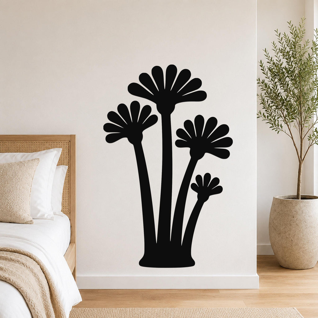 Black metal wall art with a silhouette of four fan-shaped palm trees, mounted on a white bedroom wall above a bed.