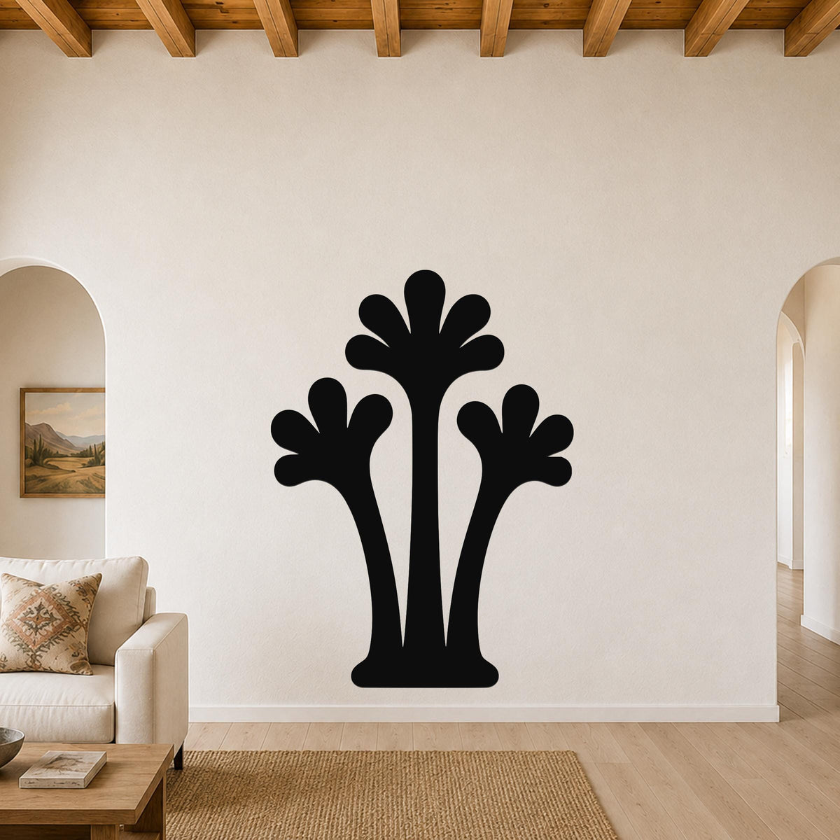 Black metal palm tree wall art with three fronded silhouettes, mounted on a living room wall above a sofa.